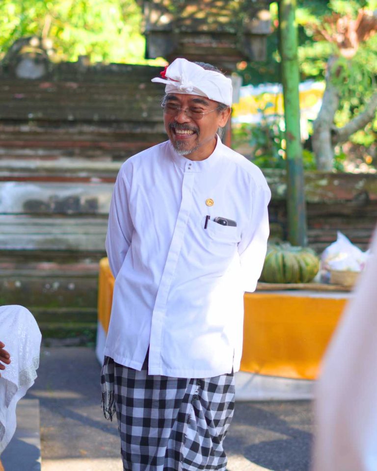 Putu Gangga smiling during a Balinese temple ceremony while participating in ngayah.